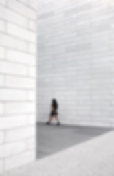 young_woman_walks_between_high_white_wal