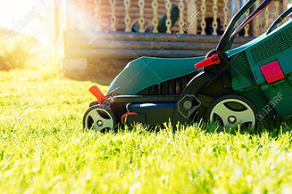 149790309-green-electric-lawn-mower-on-a-freshly-mown-lawn-in-the-garden-against-the-backg