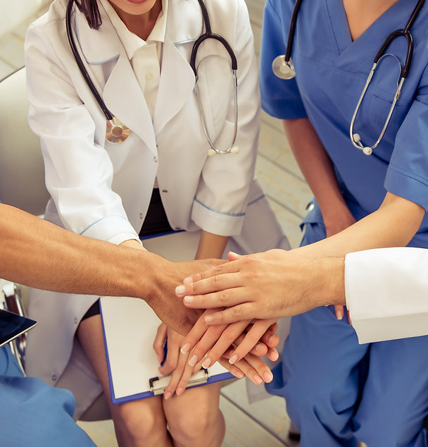Grupo de médicos y enfermeros juntando las manos en equipo