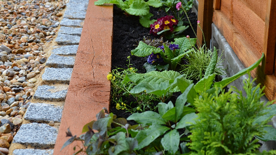 front garden with cobbles, gravel, raised beds with wooden sleepers 