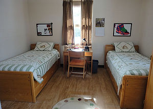 A typical dorm room on campus including beds and a desk.