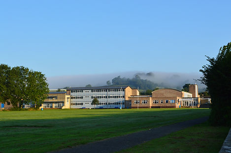 Beaminster School on a sunny day with blue sky and a bank of fog