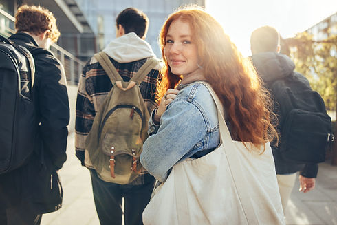 Female student glancing back while going for a class in college. Girl walking with friends