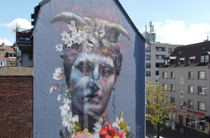 Giant Loki mural in Dusseldorf by Nomad Clan for 40Grad. stone statue and floral decoration representing transgender and intersected flora and fauna. large scale mural commission in urban environment, public artwork by international mural artist Cbloxx