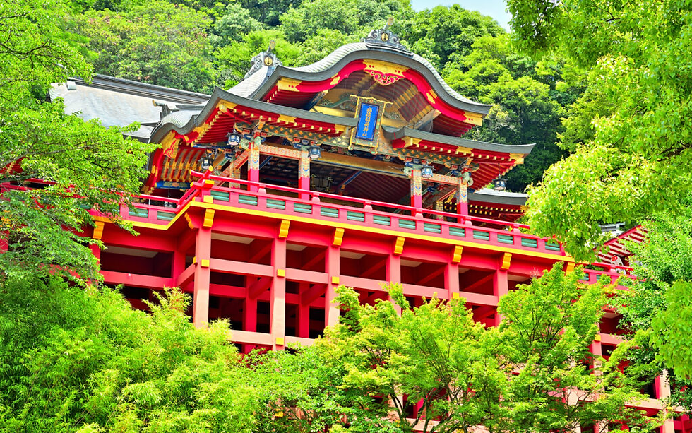 Bright red and ornately decorated, the Main Shrine of Yutoku Inari stands majestically against a lush green backdrop, showcasing traditional Japanese architecture.