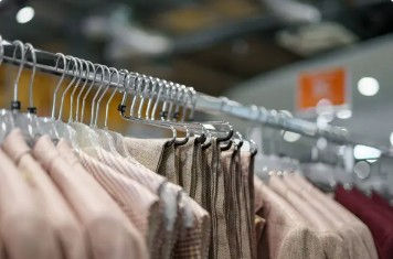 A full clothing rack with many different pieces of apparel hanging on it.