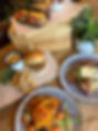 An appetizing spread featuring a burger with onion rings, a vibrant salad, a hearty open-faced sandwich, and another sandwich topped with cheese, all garnished with fresh herbs