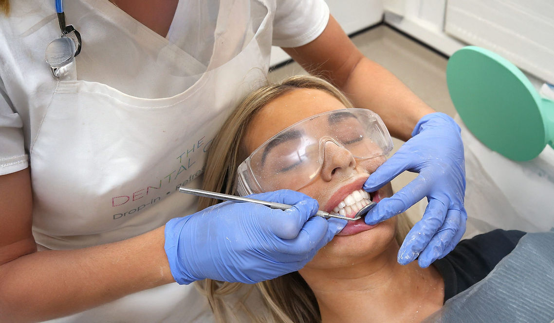 A woman wearing safety goggles receives a dental cleaning
