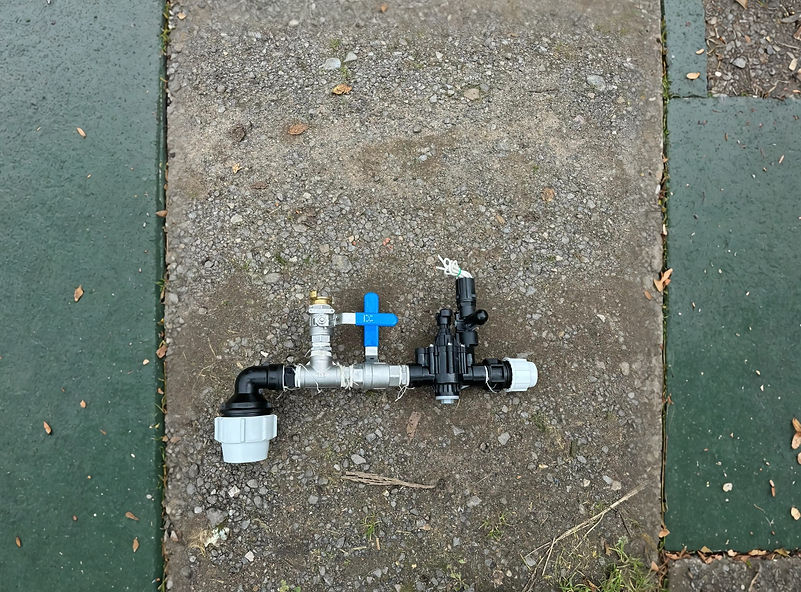 A complex pipe system on a textured concrete surface. It includes black and silver pipes