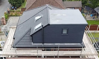 Aerial view of a house extension with a modern, gray roof and cladding. Two skylights are visible