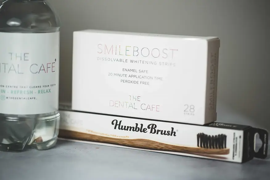Box of Smile Boost whitening strips, a Humble Brush toothbrush, and a bottle with "The Dental Cafe" label