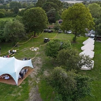 Aerial view of a campsite with a large white tent on the left and several smaller tents in a row to the right