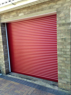Vibrant red roller garage door fitted to a brick garage
