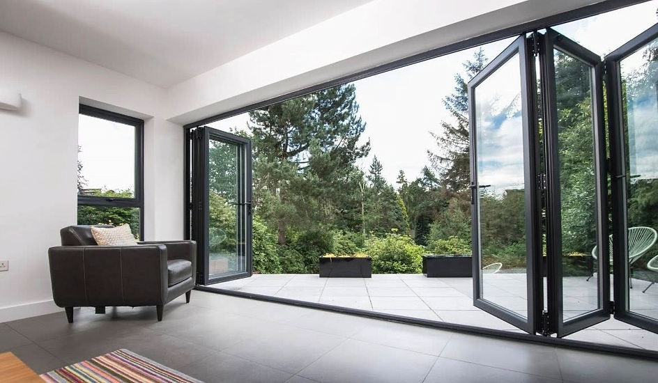 Single-story house with brick walls and large folding glass doors opening to a spacious stone patio