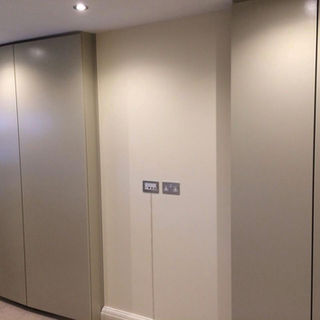 Minimalist room corner with smooth, beige cabinets blending seamlessly into a light wall