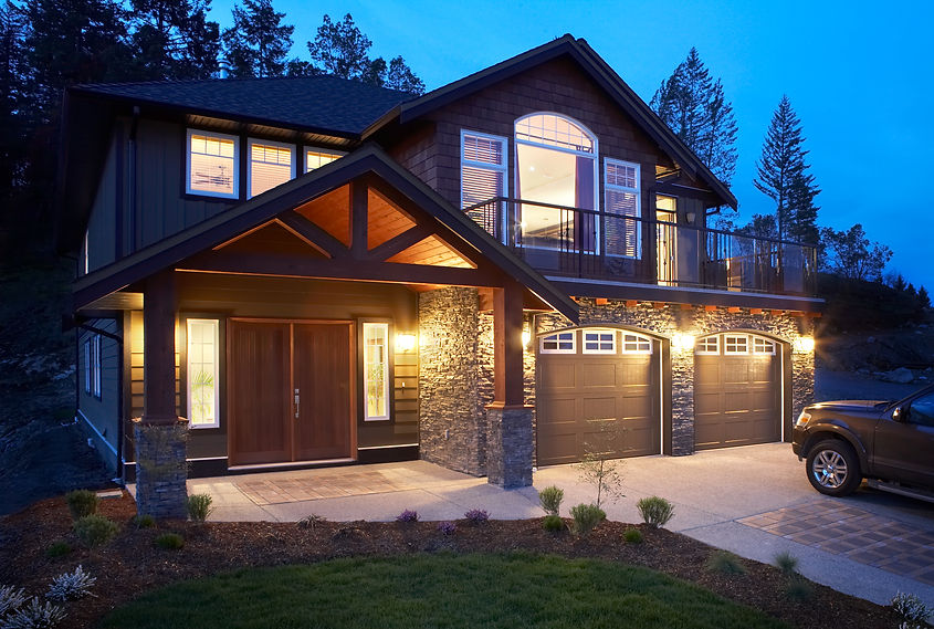 Two-story house at dusk, warmly lit with stone and wood facade