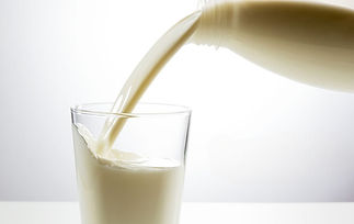 Pouring milk into a clear glass against a bright, white background