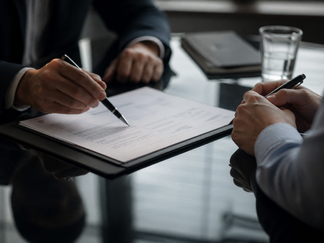 Two people signing documents at a meeting table, illustrating the financial advice consolidation deals reshaping the UK advisory sector