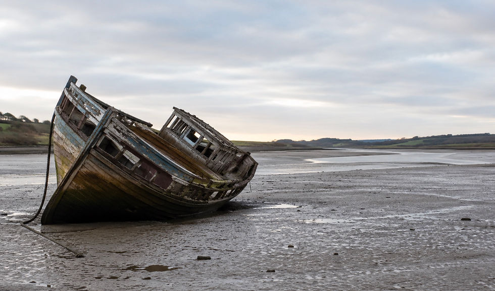 Wooden fishing boat tilted on estuary mudflats at low tide, representing the decline of active share as a fund performance predictor