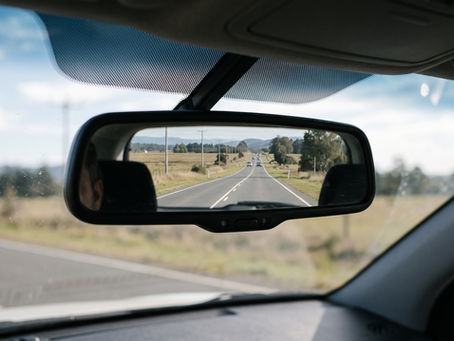 A car rear-view mirror reflecting a road stretching into the distance — illustrating why past performance is an unreliable guide to future fund returns