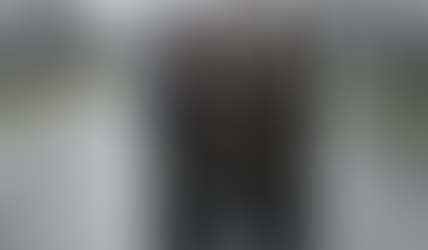 A middle-aged couple in a rain-soaked park, huddled under an umbrella but visibly wet despite it — their damp jackets and resigned expressions illustrating how active funds in downturns offer less protection than promised.