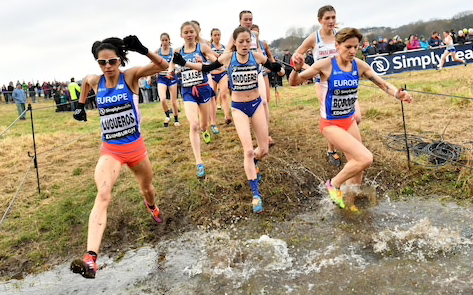 Picture of female cross country runners leaping a large puddle