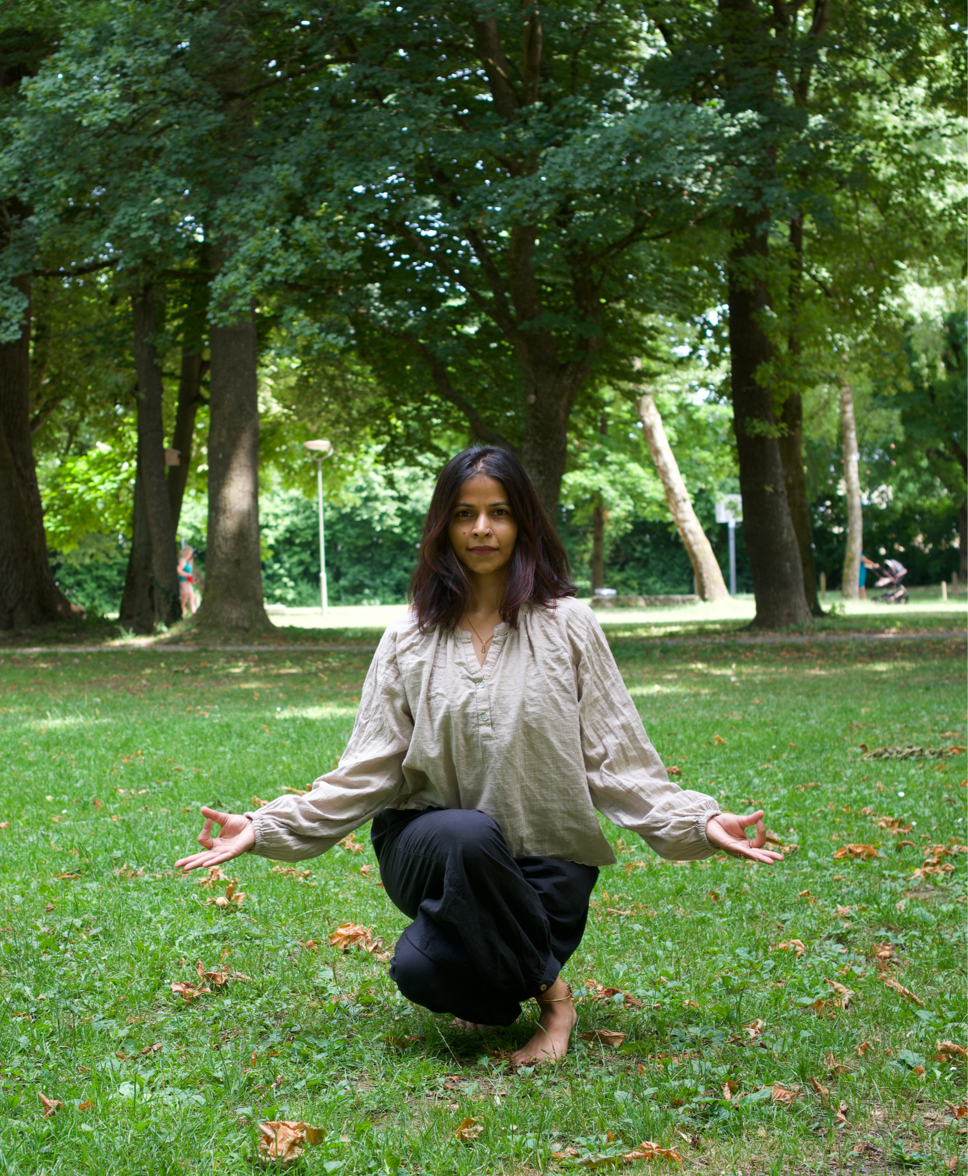 People practicing yoga in the Hermann Frieb Park surrounded by green trees.