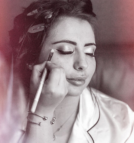Black and white image of a bride having her makeup done on her wedding day. Glitter eyeshadow.