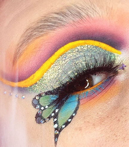Close-up of an eye with vivid butterfly-themed makeup, featuring bold colors like yellow, pink, and blue, with intricate deta