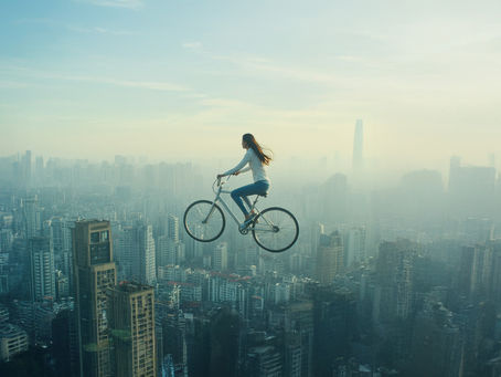Mujer sobre una bicicleta suspendida en el aire sobre la ciudad, representando la narrativa de marca con propósito y coherencia.