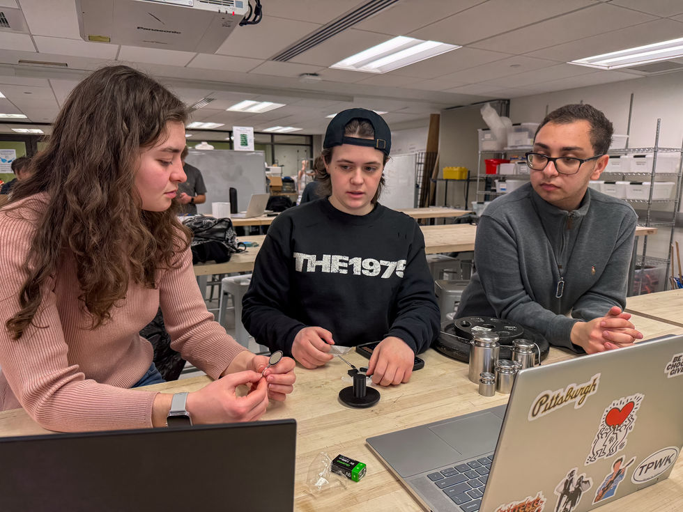 Juliana Alvelo-Davies:
Preparing for calibration of the Tekscan FlexiForce sensors used for our device. The calibration process involved gathering calibrated test masses, securing our custom sensor cradle to the workbench, seating the pressure sensor within its cutout, and placing a load distribution puck on top to ensure even force application across the sensor surface. Sensors were conditioned via repeated loading to stabilize output before their output values at each applied weight were recorded to determine their calibration equations.
Pictured (from left): Hannah Carney, Juliana Alvelo-Davies, and Kareem Mahmoud.