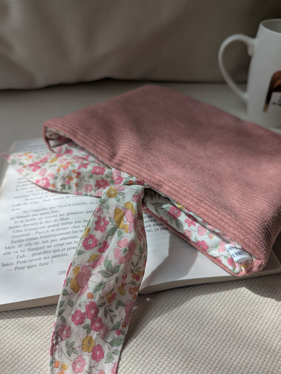 Miniature : Pochette à livre en velours rose posée sur un livre ouvert