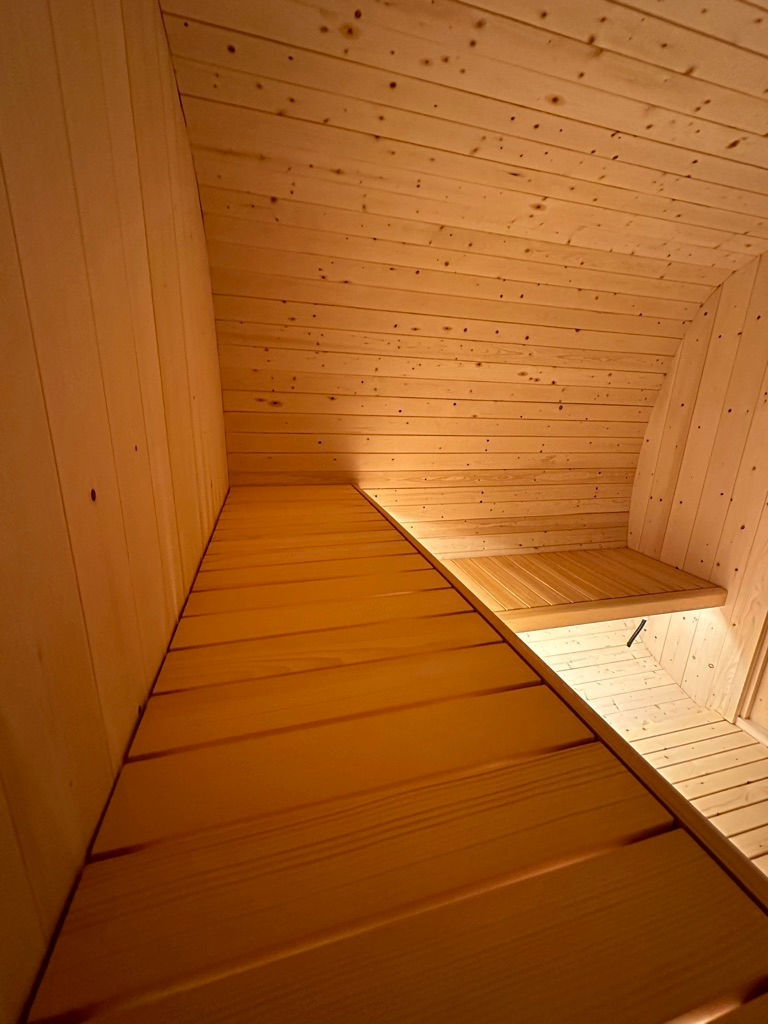 Interior wooden seating of The Kuusi Deluxe Arc Sauna