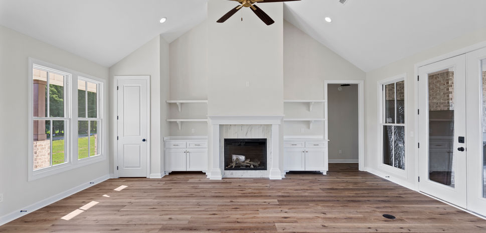 Open floor plan living room with fireplace, and wood tone flooring. Modern look.