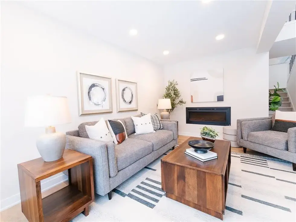 living room off of the homes entry with styled couches, fireplace, chairs and coffee table