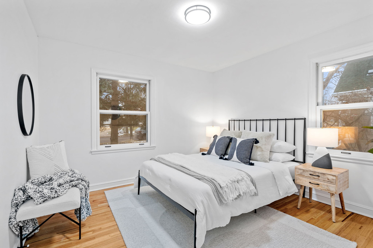 Bright bedroom with white bed, wood floor, and two windows