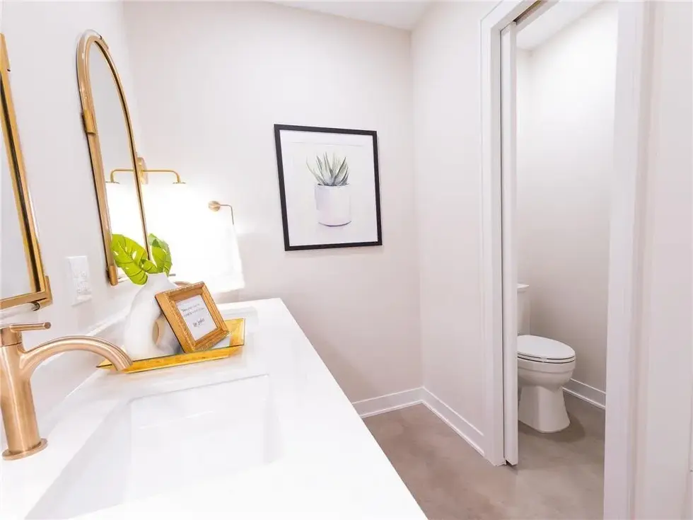 Dual sink vanity with gold accents and fixtures as well as a private toilet room