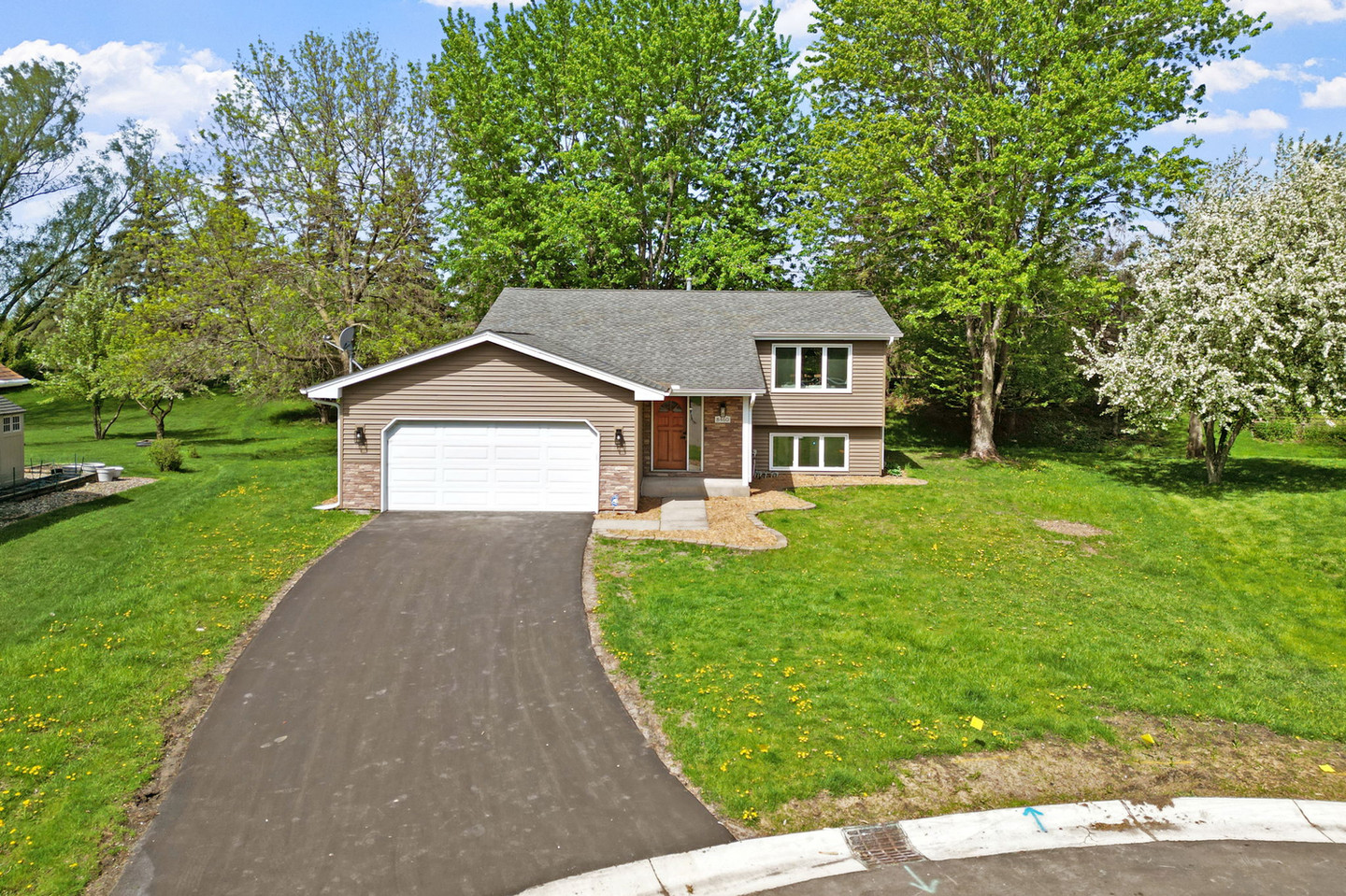 Brown house with garage and green lawn