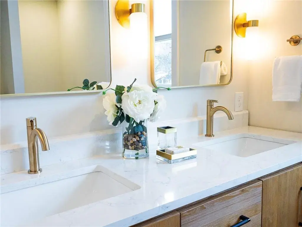 Dual sink vanity with gold fixtures and sconces placed on each side of the mirrors