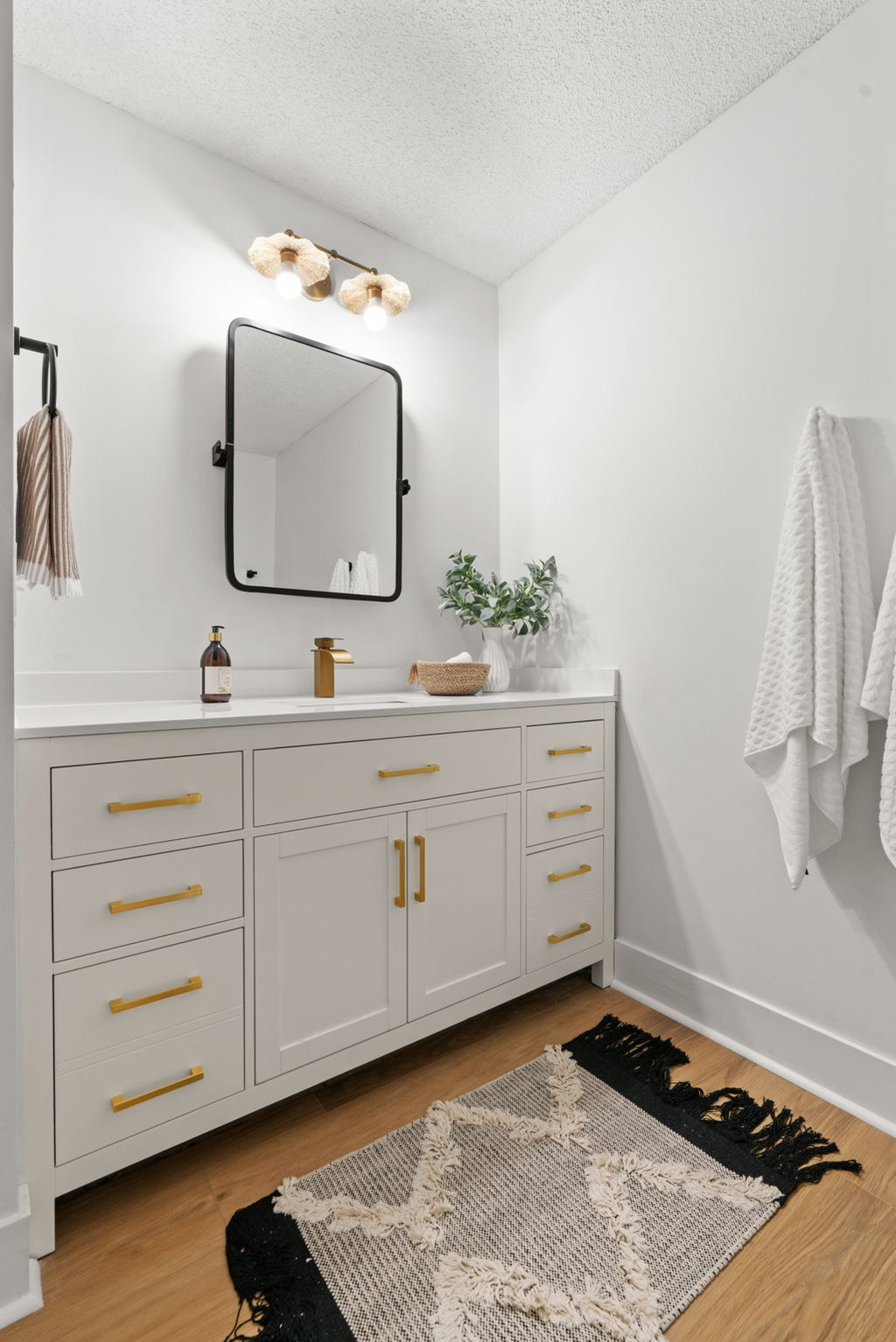 Modern white bathroom vanity, gold hardware, black mirror