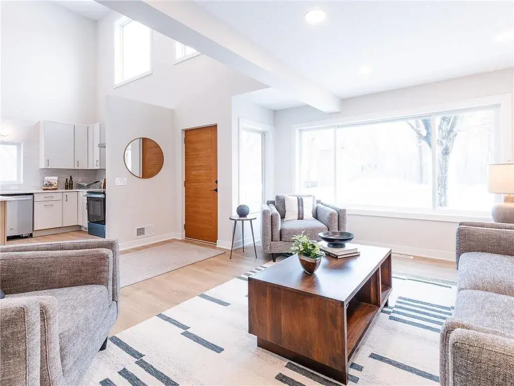living room off of the homes entry with styled couches, fireplace, chairs and coffee table