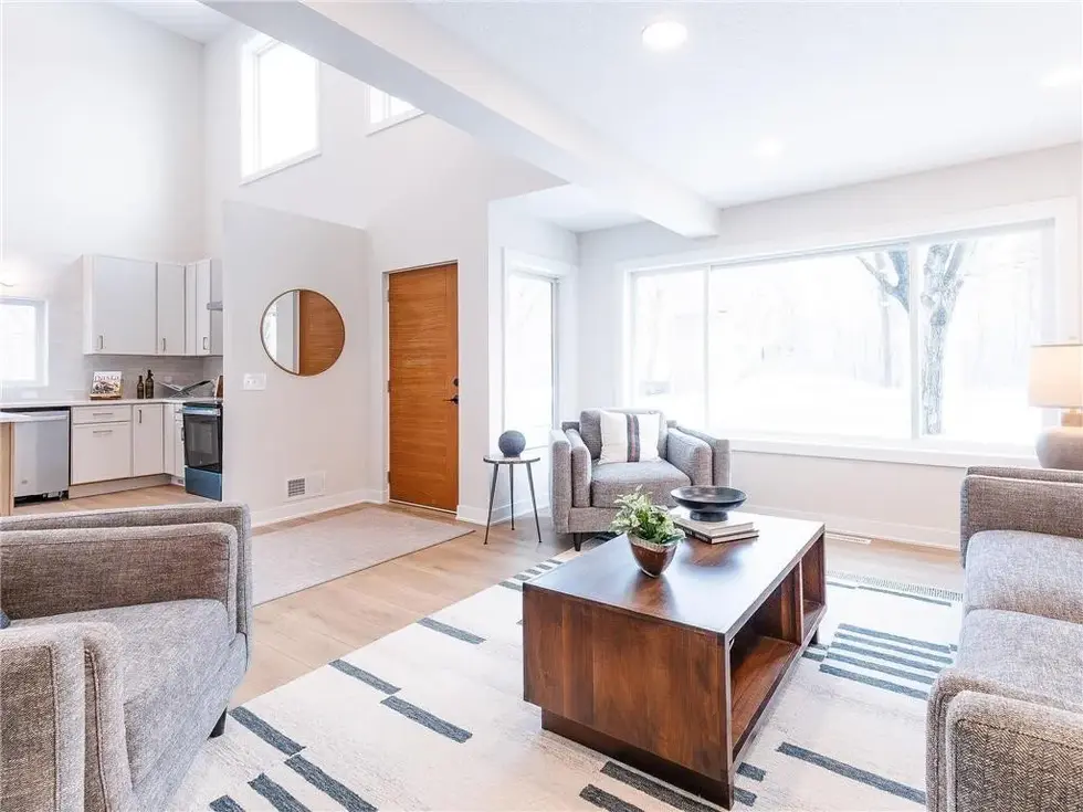 living room off of the homes entry with styled couches, fireplace, chairs and coffee table