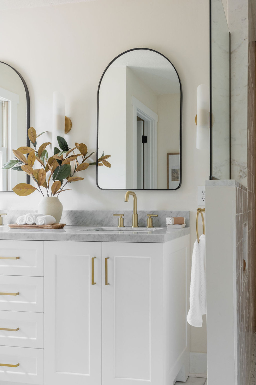 Modern bathroom vanity with gold fixtures & arched mirrors