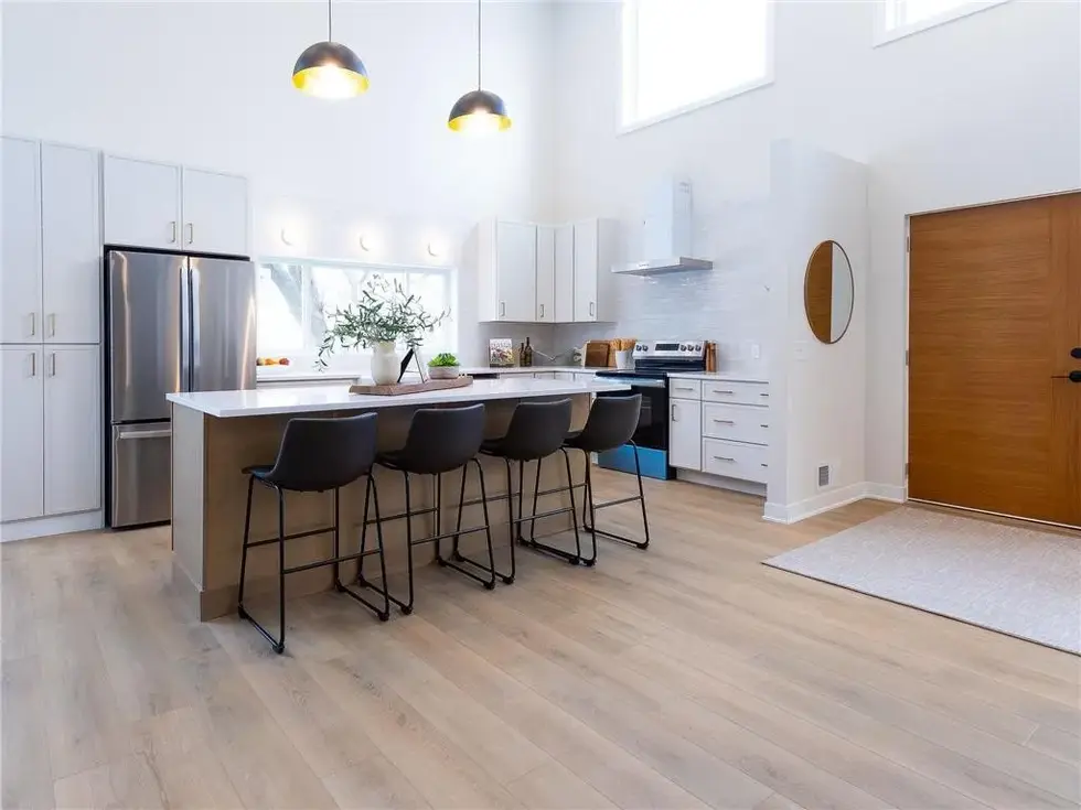close up view of finished open concept kitchen off of the entry with vaulted ceilings and kitchen island area with 4 leather barstools