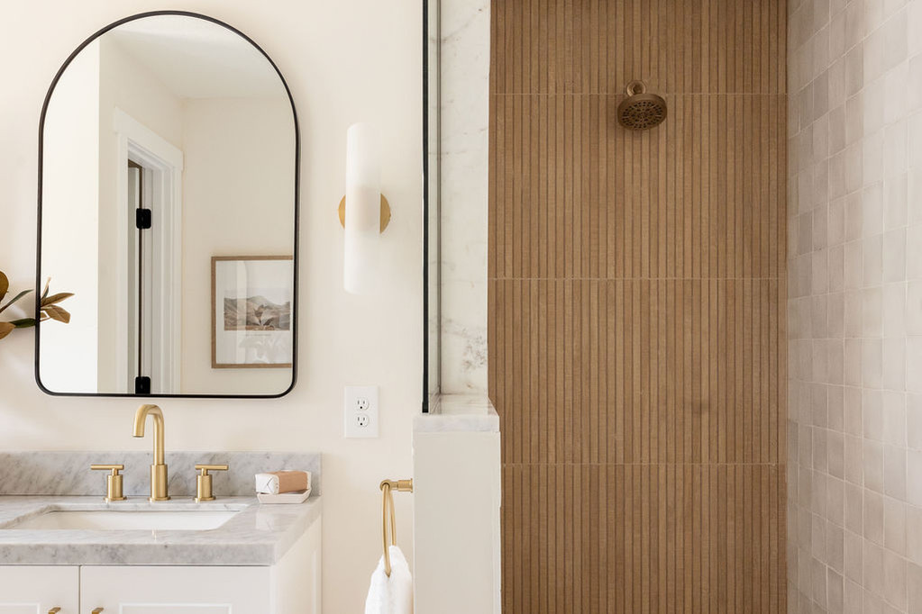 Modern bathroom vanity and shower with gold accents.