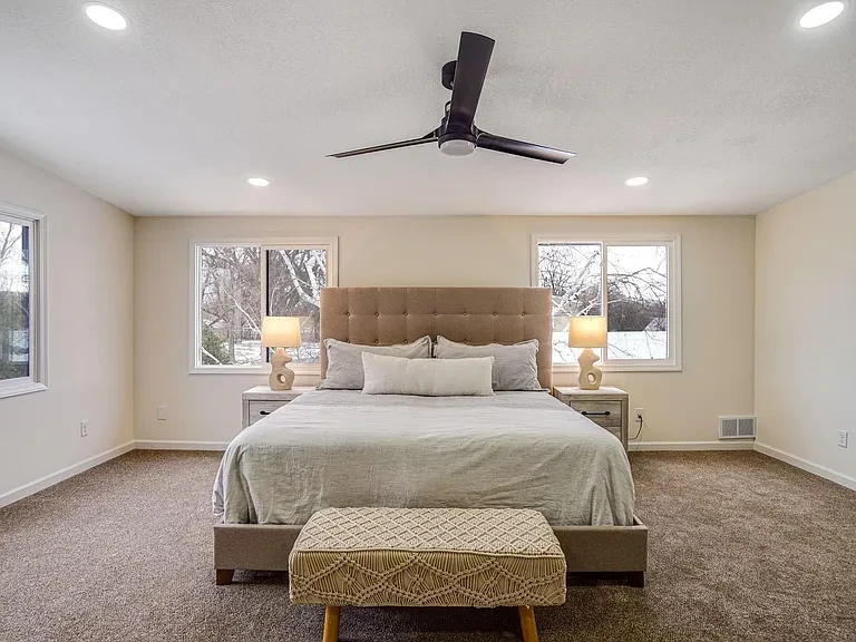 Remodeled bedroom with large bed and ceiling fan