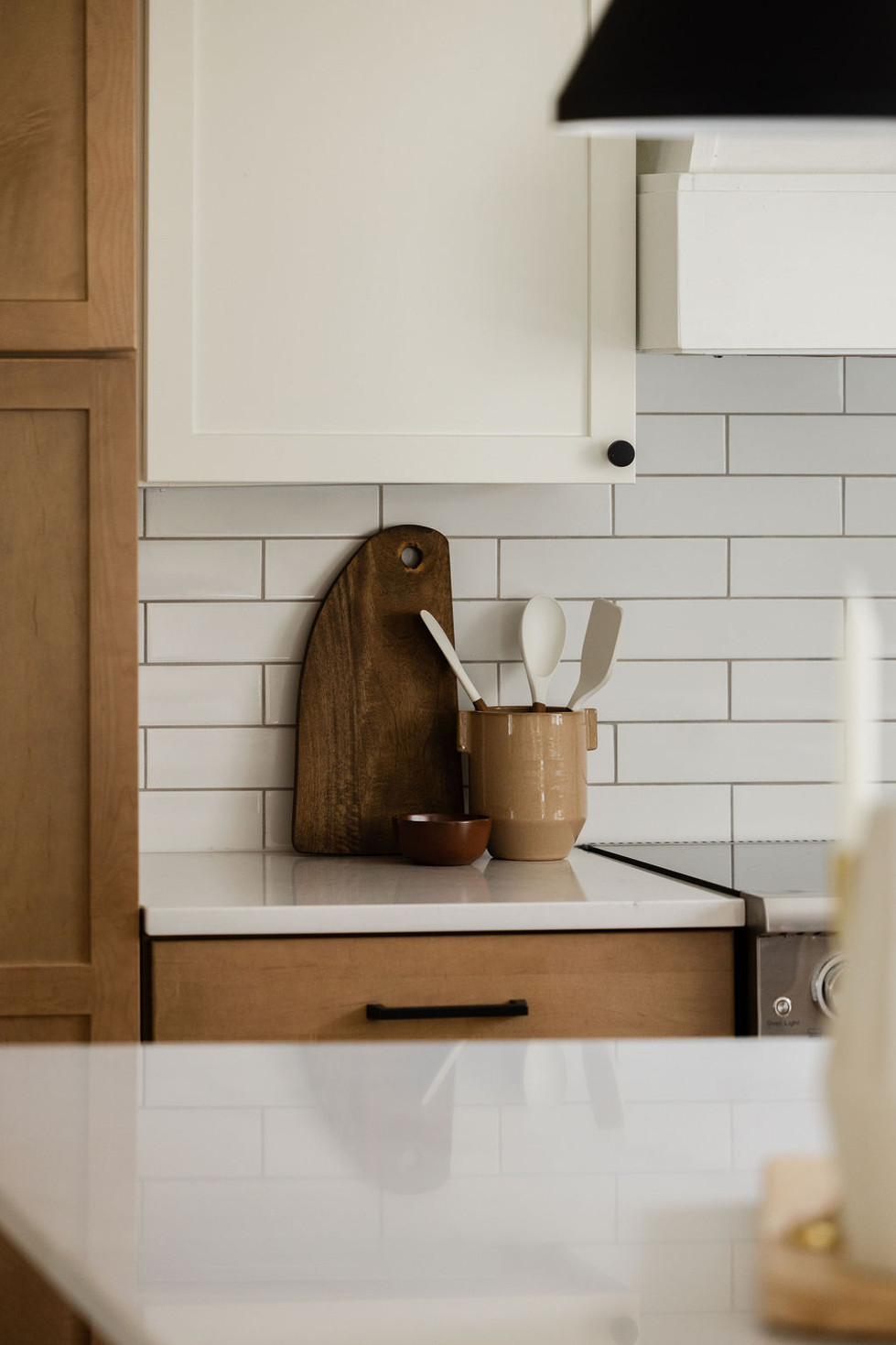 Kitchen counter with white subway tile, cutting board, and utensils