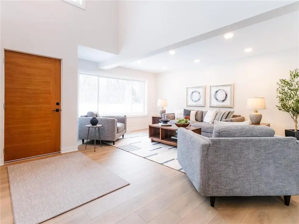living room off of the homes entry with styled couches, chairs and coffee table