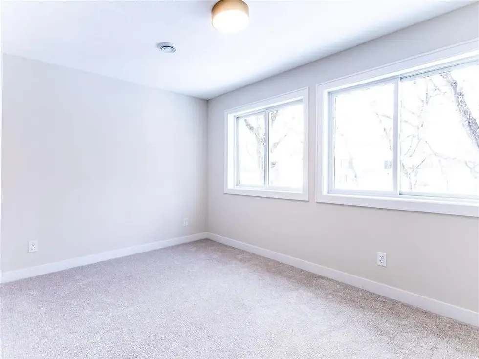 Bedroom with 2 double wide windows letting in an abundance of natural light, carpet and white trim detail