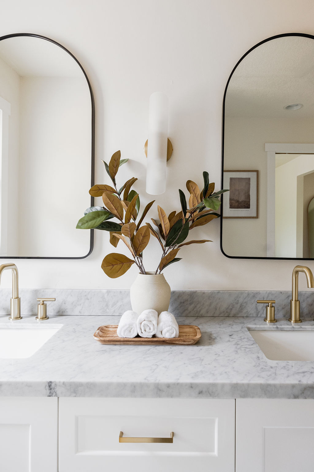 Modern bathroom vanity with gold faucets and leaf arrangement